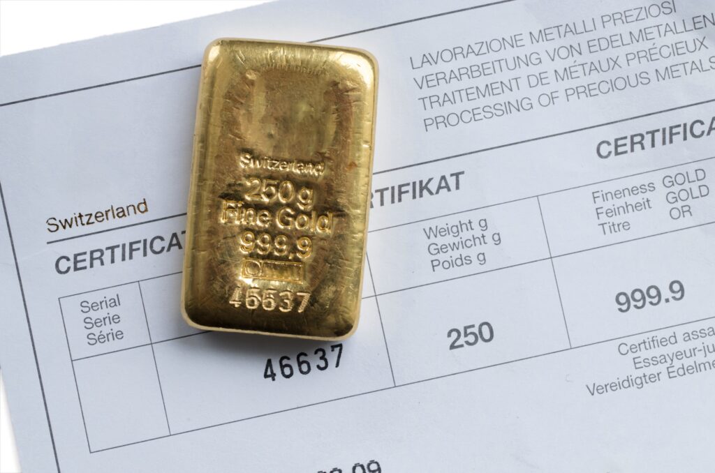 Un lingotto d'oro da 250 g appoggiato su un certificato del produttore