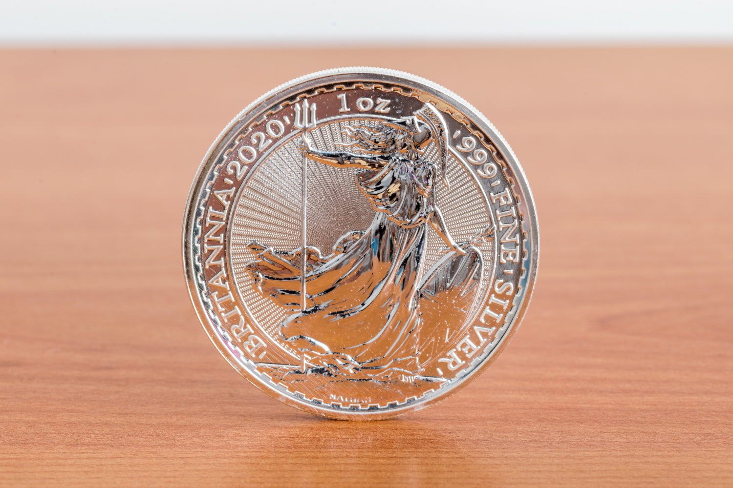 A silver Britannia coin on a wooden table.