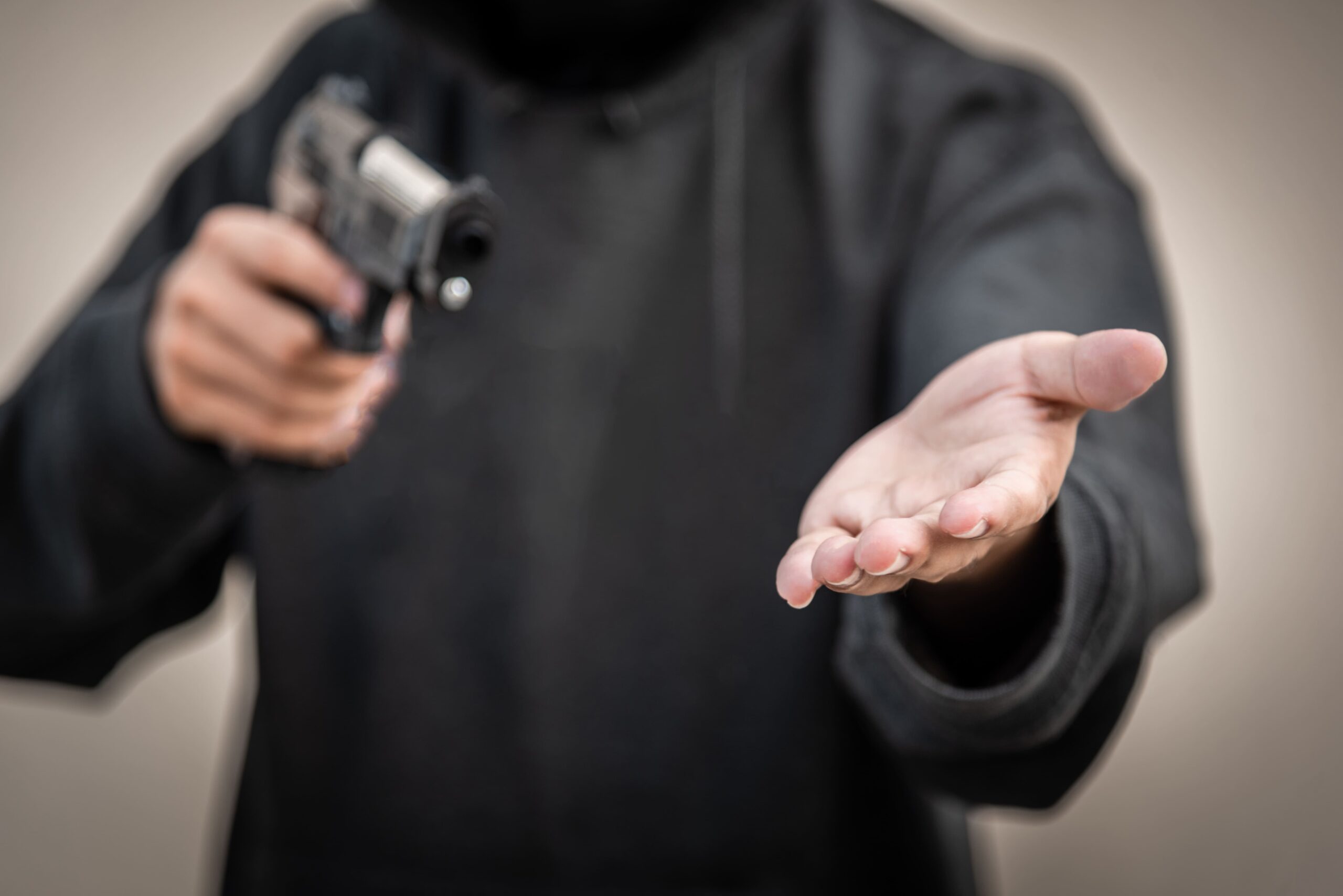 Un homme vêtu de noir menace sous la menace de son arme