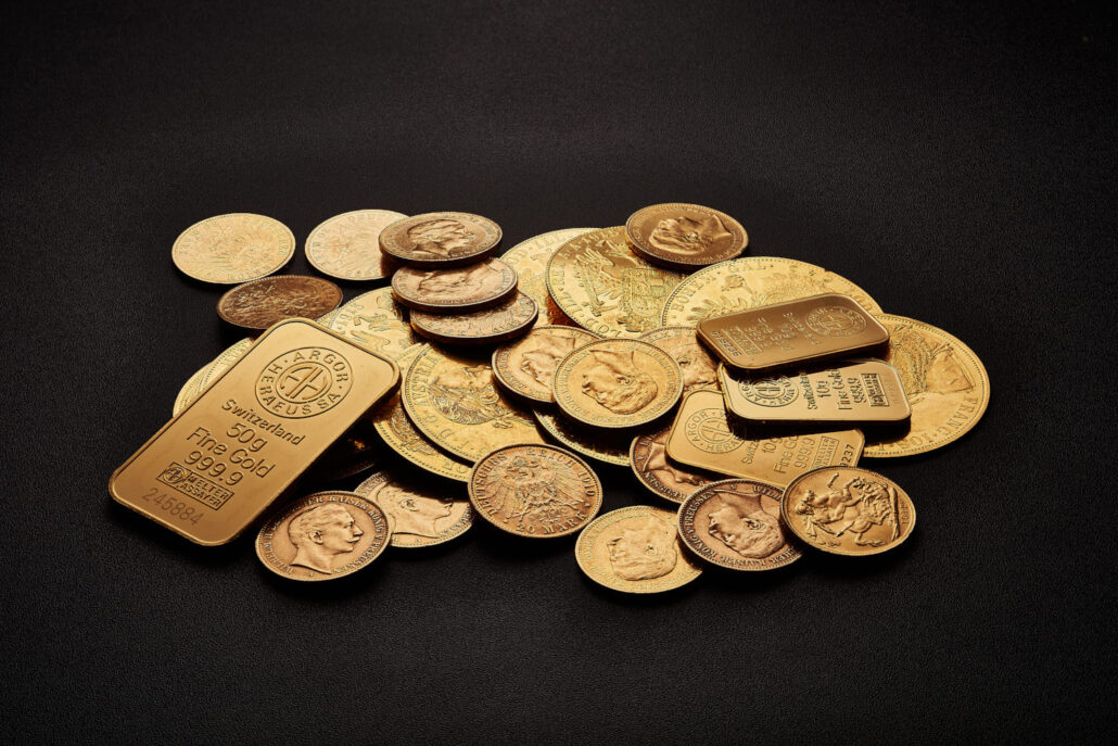 verschiedene Goldmünzen und -Barren auf schwarzem Hintergrund
